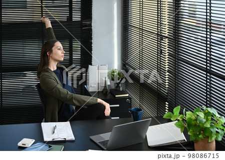 Peaceful caucasian businesswoman taking a break, relaxing on cozy office chair and stretching arms 98086715