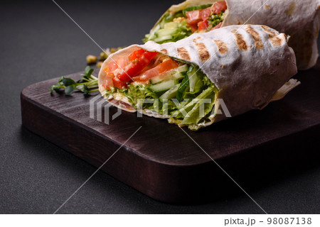 Delicious fresh shawarma with tomatoes, peppers, cucumber on a dark concrete background 98087138
