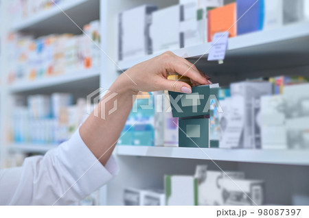 Close up picture of pharmacists hand taking a box with medicine Close up picture of pharmacists hand taking a box with medicine 98087397