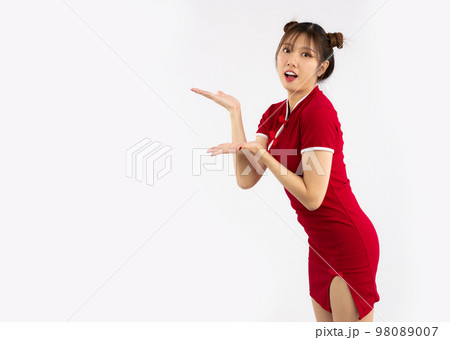 Chinese new year concept. Young Asian woman wearing red traditional chinese dress with gesture of introduce isolated on white background.. 98089007
