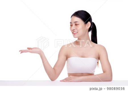 Beautiful Asian woman wearing spa clothes smile and pointing finger to an empty palm isolated on yellow background studio portrait. Beautiful Asian woman wearing spa clothes smile and pointing finger to an empty palm isolated on yellow background studio portrait. 98089036