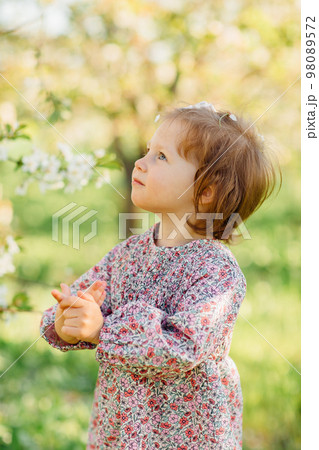 a pretty little girl by a flowering tree in a spring garden a pretty little girl by a flowering tree in a spring garden 98089572