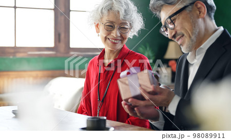 プレゼントを渡すシニアカップル 98089911
