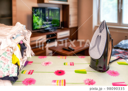 Ironing big pile of laundry and watching television Ironing big pile of laundry and watching television 98090335