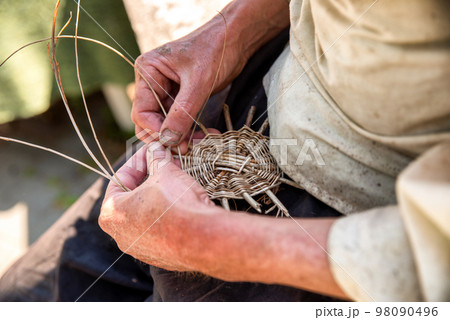 Hands of the senior craftsman while weaving wicker basket. Traditional Slovak folk craft. Hands of the senior craftsman while weaving wicker basket. Traditional Slovak folk craft. 98090496
