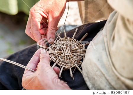 Hands of the senior craftsman while weaving wicker basket. Traditional Slovak folk craft. Hands of the senior craftsman while weaving wicker basket. Traditional Slovak folk craft. 98090497