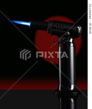 A gas blow torch kitchen with blue flame on the black background. 98090742