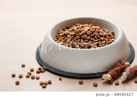 A bowl of dog food on a wooden floor. 98090927