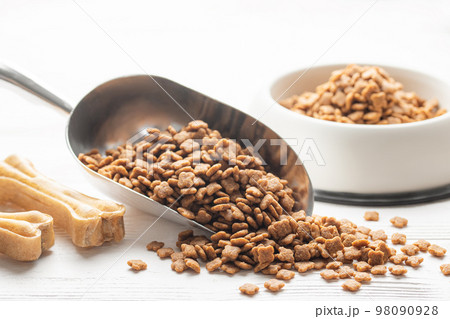 Dry pet food in scoop on white wooden background. Dry pet food in scoop on white wooden background. 98090928