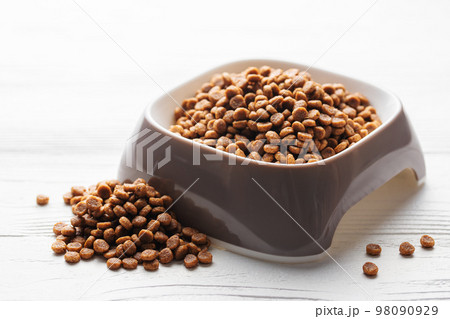A bowl of dog food on a wooden floor. 98090929