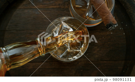Close-up of pouring whiskey or rum on old wooden barrel 98091131