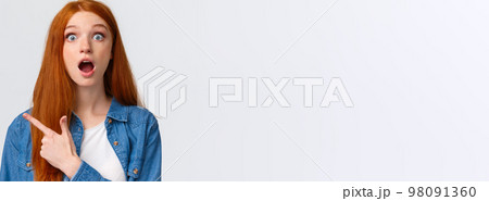 Close-up portrait impressed shook and speechless pretty redhead female student, teenager pointing upper left corner drop jaw, discussing amazing banner, product advertisement, white background 98091360
