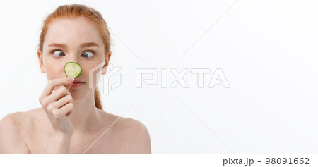 Close up beauty portrait of a smiling beautiful half naked woman holding cucumber slices at her face isolated over white background 98091662