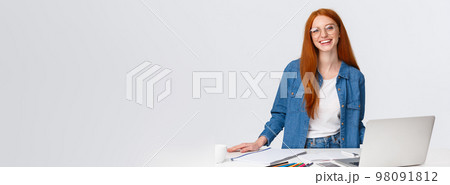 Creativity, lifestyle and education concept. Cute charismatic redhead girl in glasses standing near table and laptop, prepare colored pencils and staff to draw, learning art or design online courses 98091812