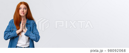 Waist-up portrait nervous redhead female student need help asap, hold hands over chest together in pray, smiling worried and impatient stare camera, pleading, begging favour 98092068