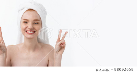 Beautiful caucasian woman applying mask on her face with two fingers sign white background. 98092659