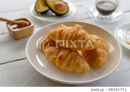 Croissant with egg,avocado on white dish and honey, coffee. breakfast and healthy food concept. Croissant with egg,avocado on white dish and honey, coffee. breakfast and healthy food concept. 98092751
