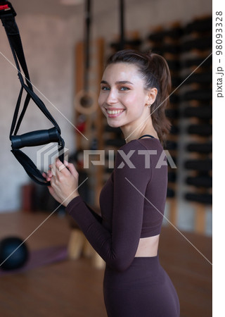 Fit woman standing in the gym with trx 98093328