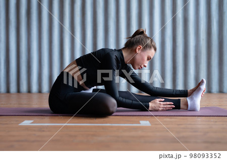 Woman leans forward stretches her back and legs. 98093352