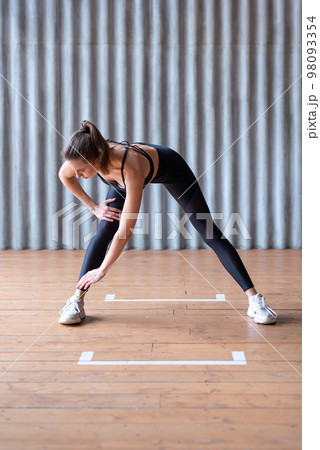 Woman exercising standing forward bend stretches of legs and lower back. Woman exercising standing forward bend stretches of legs and lower back. 98093354