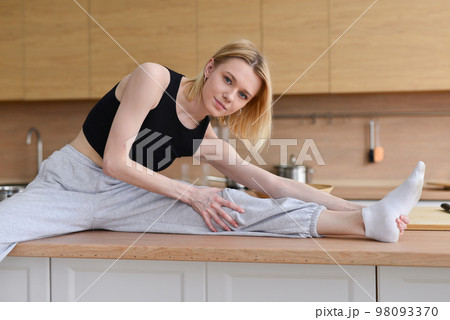 Woman sitting on table doing stretching Woman sitting on table doing stretching 98093370