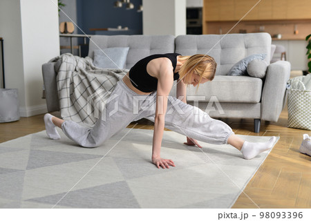 Woman working up forward splits warming up her legs. 98093396