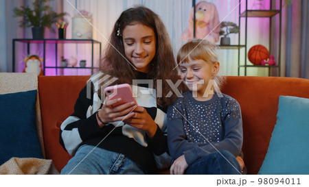 Teen sisters kids celebrate success win scream rejoices while doing online shopping on smartphone 98094011