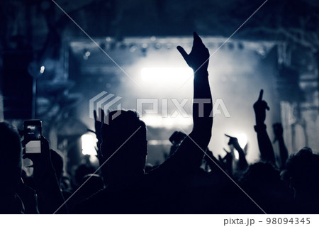 Crowd at a music concert, audience raising hands up, toned 98094345