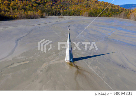 Aerial view of a church tower with cross, buried under mud and mining residuals 98094833