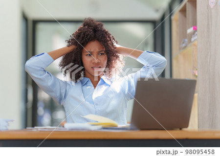 Portrait thoughtful confused young african american businesswoman looking at laptop. Stress while reading news, report or email. Online problem, finance mistake, troubleshooting Portrait thoughtful confused young african american businesswoman looking at laptop. Stress while reading news, report or email. Online problem, finance mistake, troubleshooting 98095458