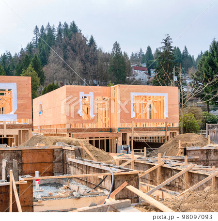 Wooden frame of new house with concrete filled fundation in front 98097093