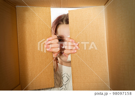 kid girl, teenager, unpacking and opening carton box, and looking inside with surprise. kid girl, teenager, unpacking and opening carton box, and looking inside with surprise. 98097158