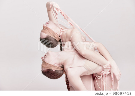 Beauty. Portrait of two young girls posing in underwear and ropes with eyes closed over light studio background. Concept of weird people, contemporary photography 98097413