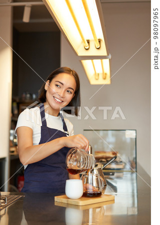 Cute korean barista girl, pouring coffee, prepare filter batch brew pour over, working in cafe Cute korean barista girl, pouring coffee, prepare filter batch brew pour over, working in cafe 98097965