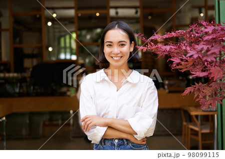 Young asian woman, cafe owner or manager, standing confident with arms crossed on hands, smiling and looking at camera Young asian woman, cafe owner or manager, standing confident with arms crossed on hands, smiling and looking at camera 98099115