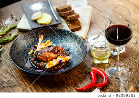 Corn chicken supreme. Beluga lentils, Old Ammerlander cheese, mini zucchini, red wine sauce. Delicious healthy traditional food closeup served for lunch in modern gourmet cuisine restaurant Corn chicken supreme. Beluga lentils, Old Ammerlander cheese, mini zucchini, red wine sauce. Delicious healthy traditional food closeup served for lunch in modern gourmet cuisine restaurant 98099583