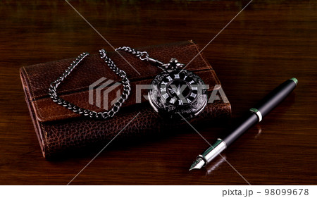 Leather Wallet with Pocket Watch and Fountain Pen on a Wooden Table Top 98099678