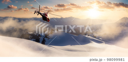 Helicopter flying over the Rocky Mountains during a colorful sunset. Aerial View from BC, Canada Helicopter flying over the Rocky Mountains during a colorful sunset. Aerial View from BC, Canada 98099981