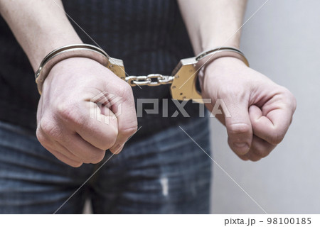 Man detained in handcuffs. Prisoner or arrested man in handcuffs 98100185