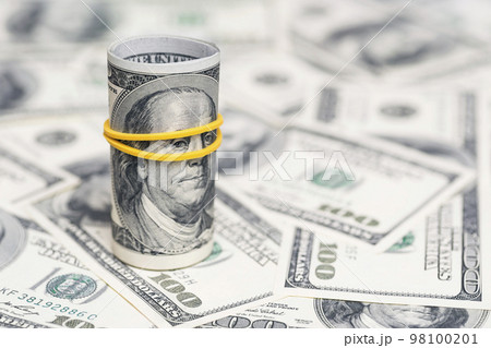 A roll of 100 dollar bills close-up on a pile of American dollars A roll of 100 dollar bills close-up on a pile of American dollars 98100201