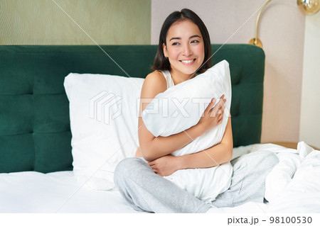 Romantic smiling asian girl lying in her bed, hugging pillow and gazing dreamy, lazy mornings in bedroom Romantic smiling asian girl lying in her bed, hugging pillow and gazing dreamy, lazy mornings in bedroom 98100530