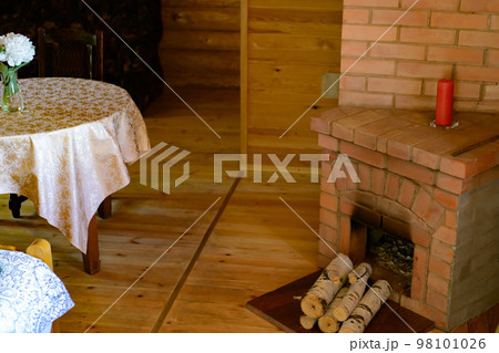 room in a rustic wooden house with fireplace, table and vase with flowers 98101026