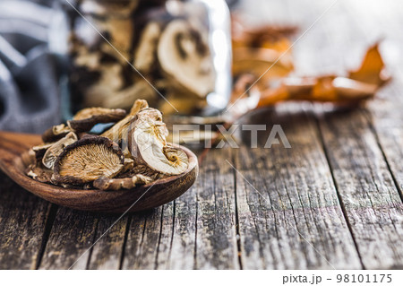 Sliced dried mushrooms in wooden spoon on wooden table. 98101175