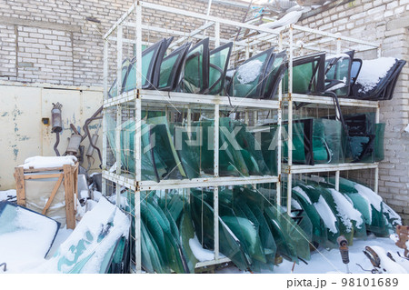 Metal shelving with used windshields removed from disassembled cars for their further sale. Metal shelving with used windshields removed from disassembled cars for their further sale. 98101689