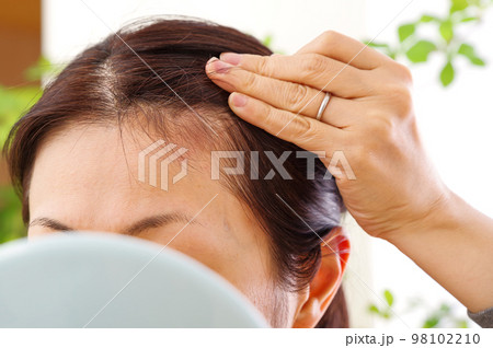 髪の毛を気にする仕草をする40代女性 98102210