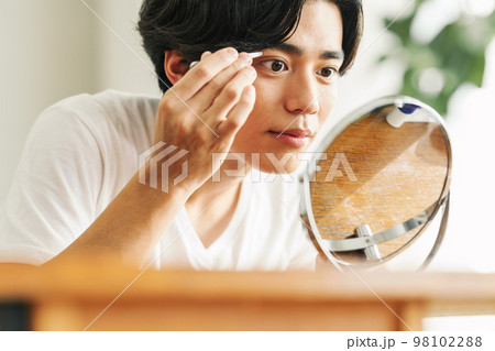 毛抜きで眉を整える若い男性 98102288