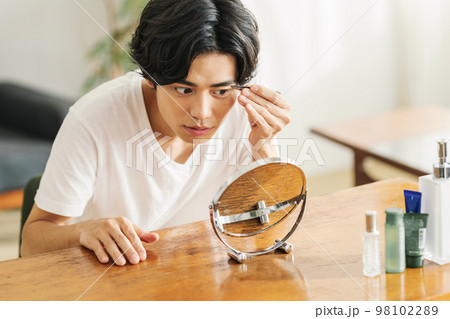毛抜きで眉を整える若い男性 98102289