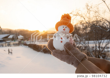 夕暮れ時に雪だるまを持つ女性 夕暮れ時に雪だるまを持つ女性 98104732