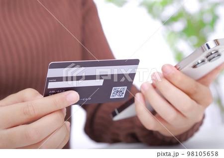 クレジットカードの情報をスマホに入力する女性 98105658