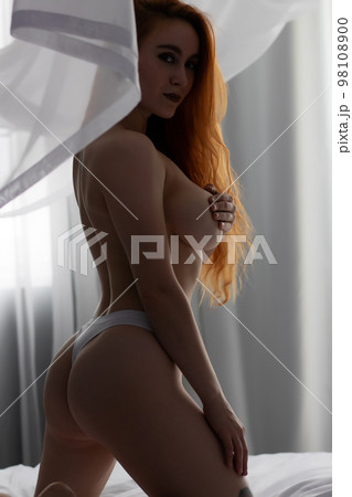Sensual woman undressing on bed Sensual woman undressing on bed 98108900